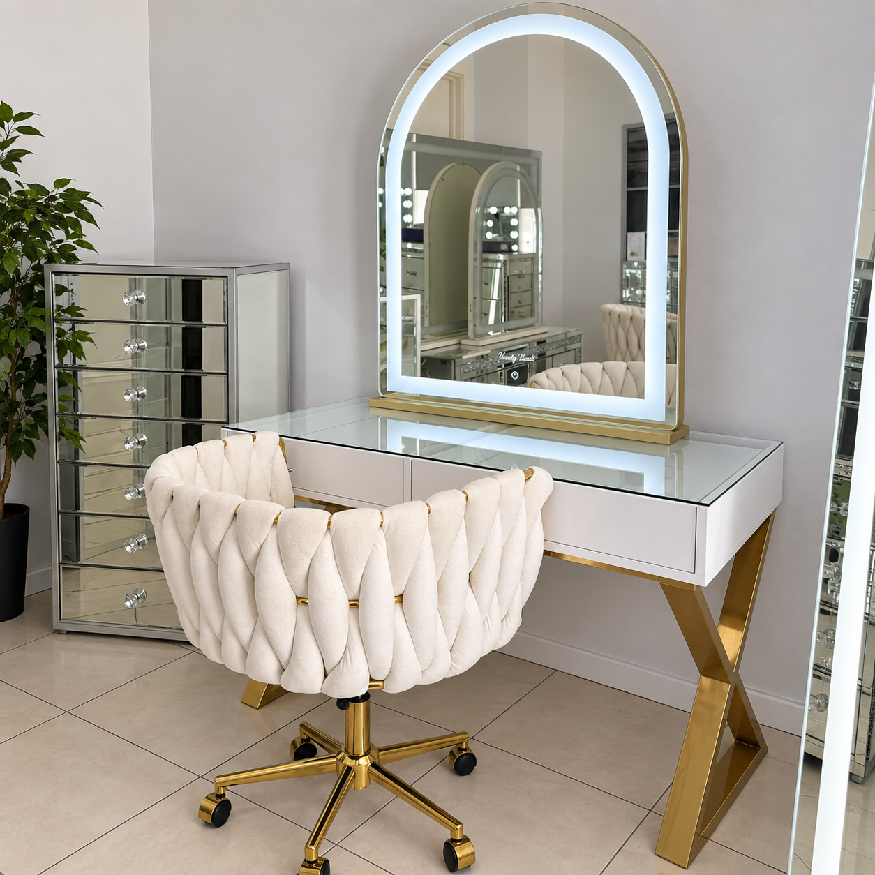 White compact vanity with a round illuminated mirror and cream upholstered chair.