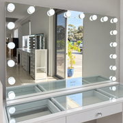 Aurora Dream makeup mirror with illuminated bulbs and touch controls, displayed on a glass-top vanity in the showroom