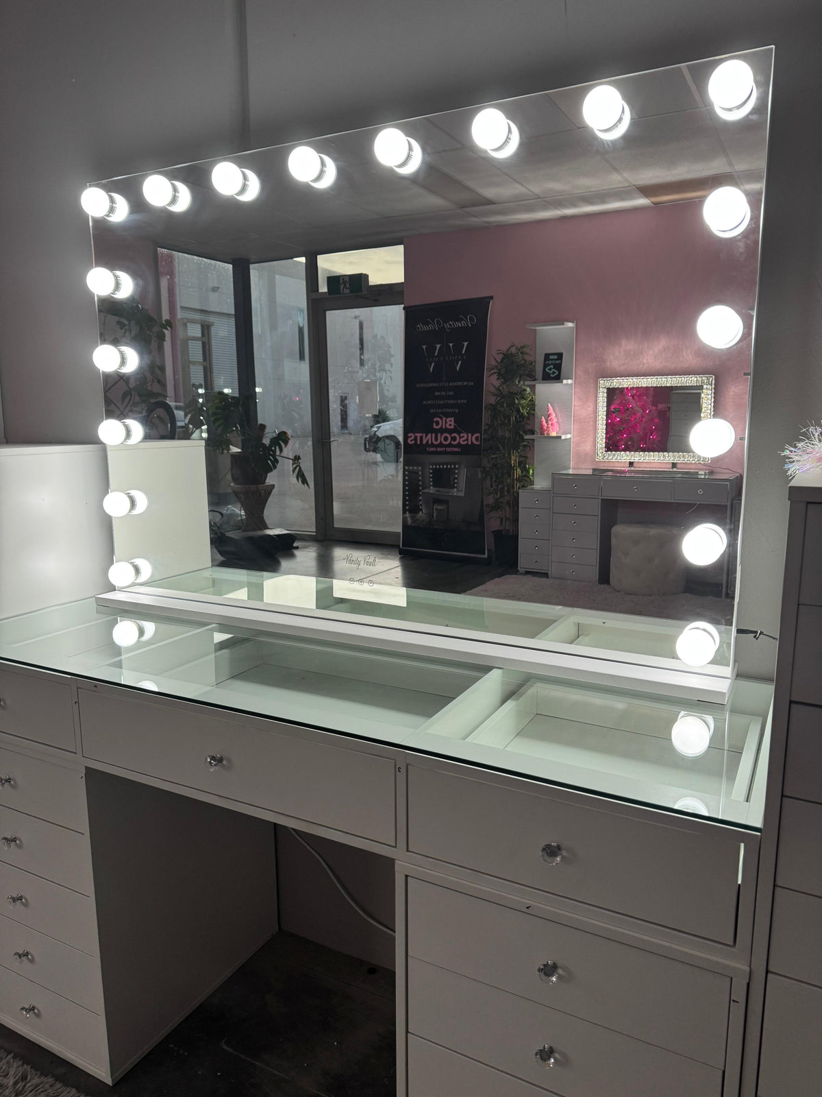Close-up of the illuminated Aurora Dream mirror on a white glass-top vanity in the showroom.