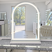 Mini Aries 80 x 60 cm white makeup mirror with illuminated arched LED border and white base in the showroom