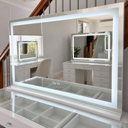Nova XL makeup mirror with illuminated rectangular LED border on a glass-top vanity in the Vanity Vault showroom